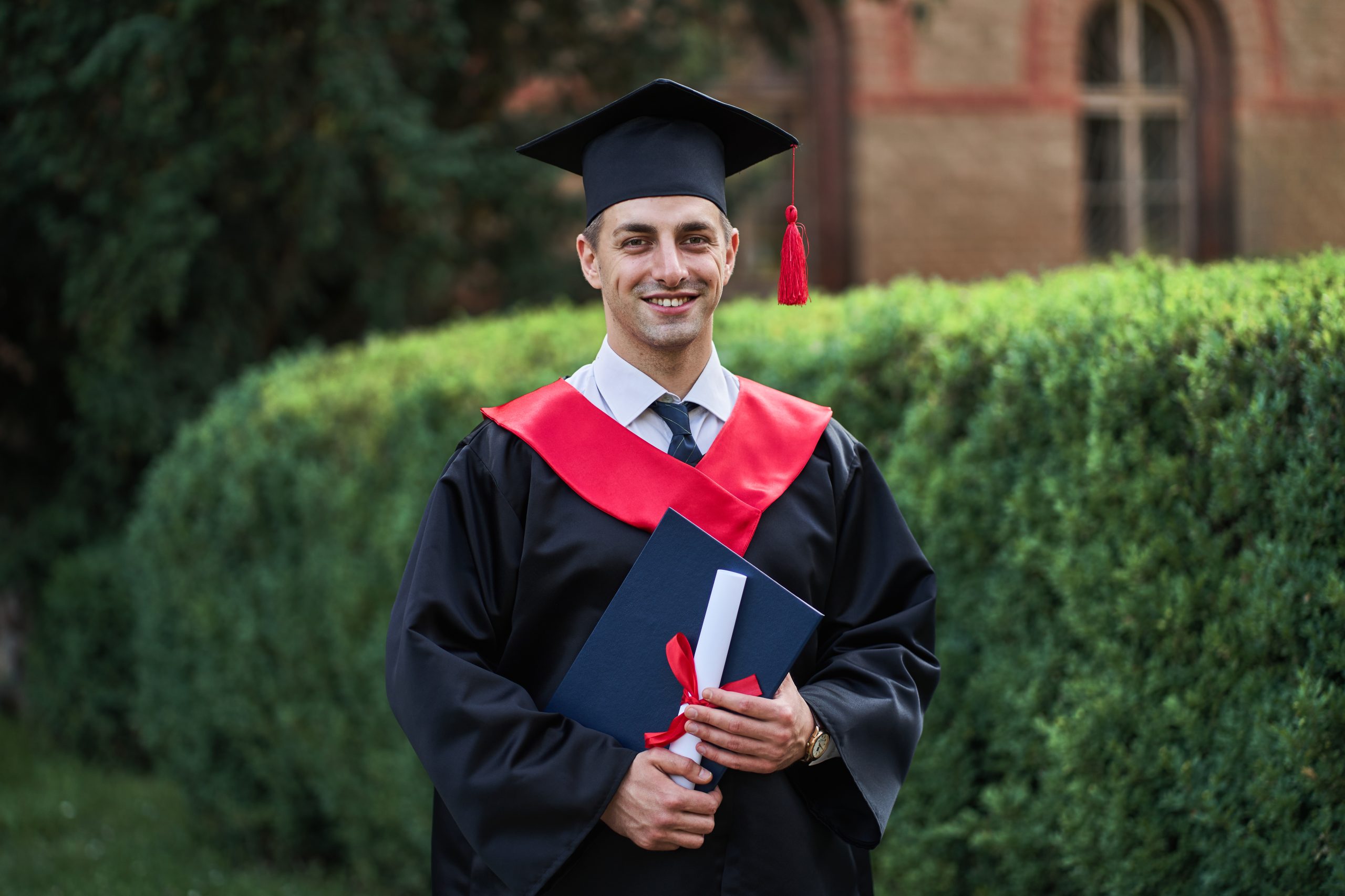 Happy caucasian male graduate in graduation glow with diploma lo